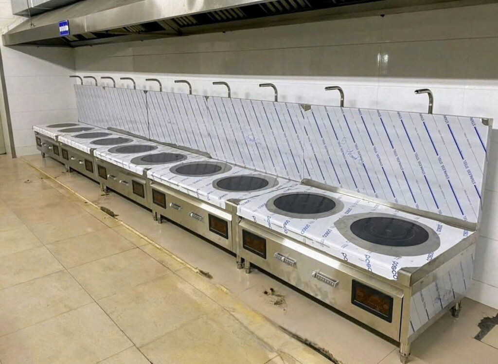 Kỹ thuật viên đang định vị và lắp đặt bếp xào chảo từ, bếp hầm từ vào đúng vị trí đã đánh dấu cho bếp công nghiệp.