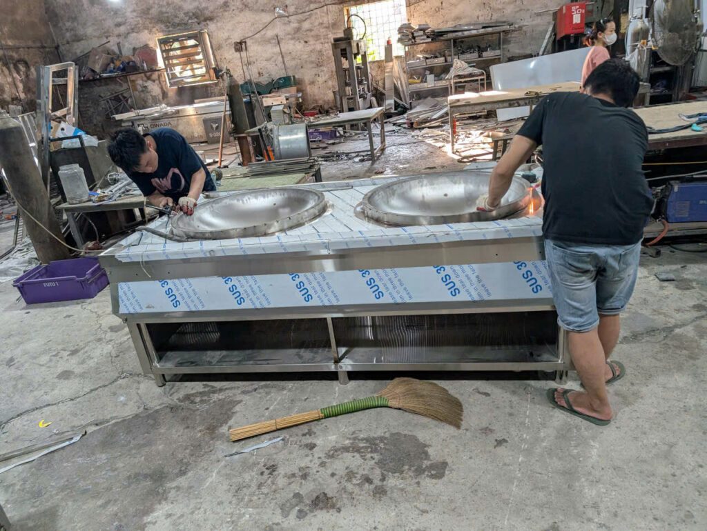 Kỹ thuật viên đang vận hành thử bếp từ công nghiệp, kiểm tra các chức năng và hiệu suất làm việc thực tế.